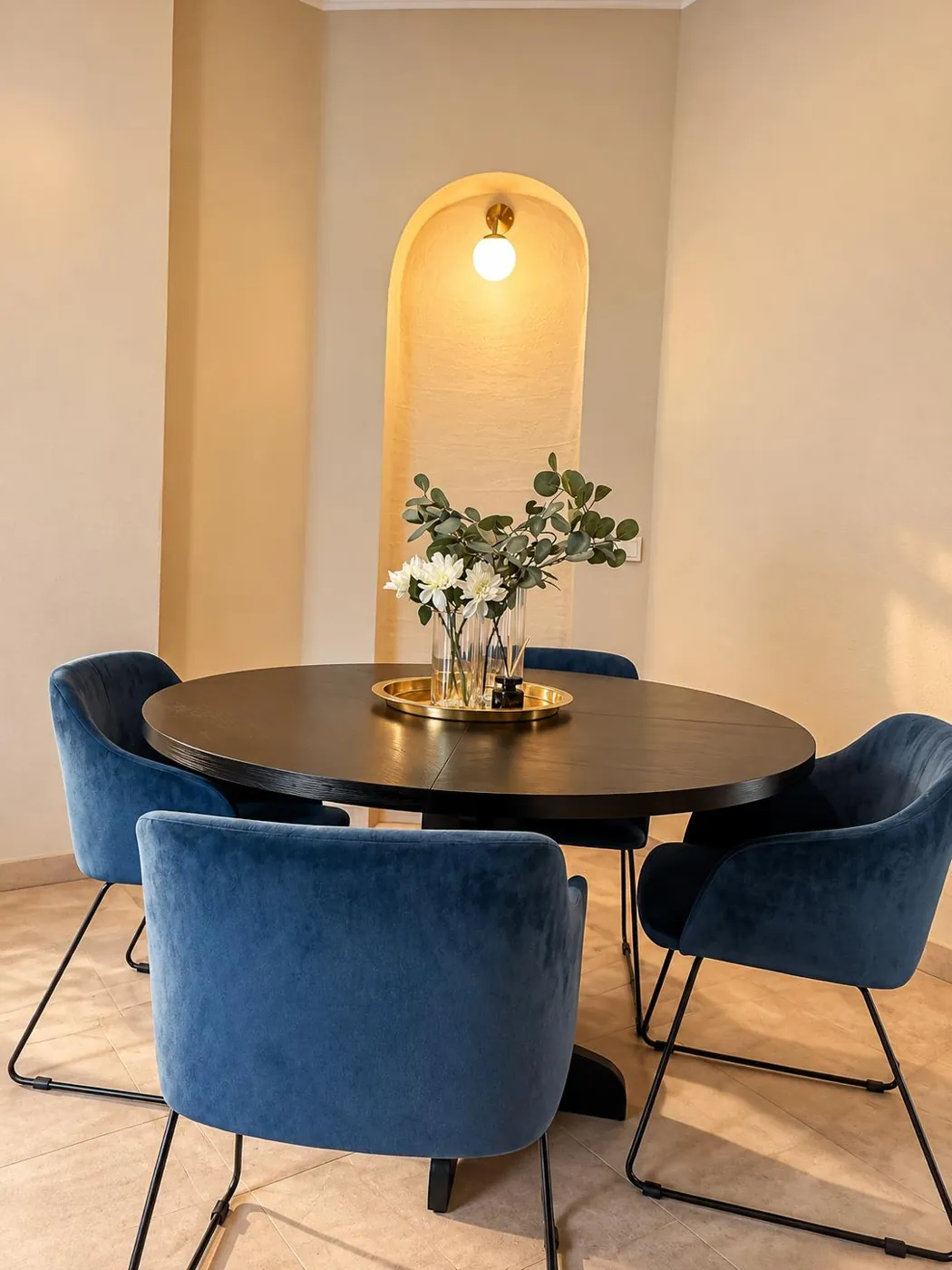 Runder Tisch mit blauen Samtstühlen in einer beleuchteten Nische, Maison Vallon · Aubin